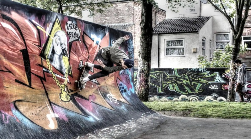 photo of a skater performing a skill in a skate park in a vegitated residential area