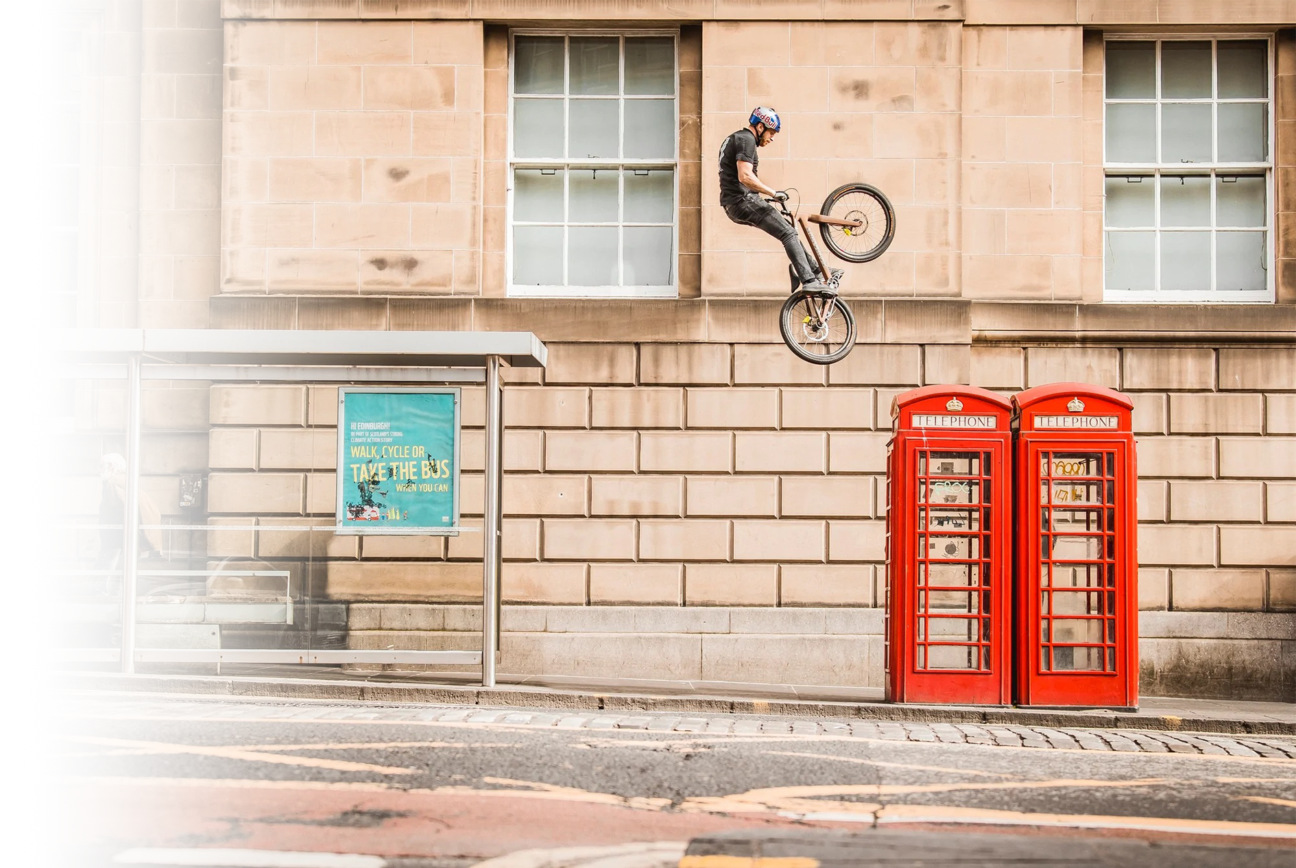 photo of person on a bmx bike performing a mid air stunt in the middle of a street